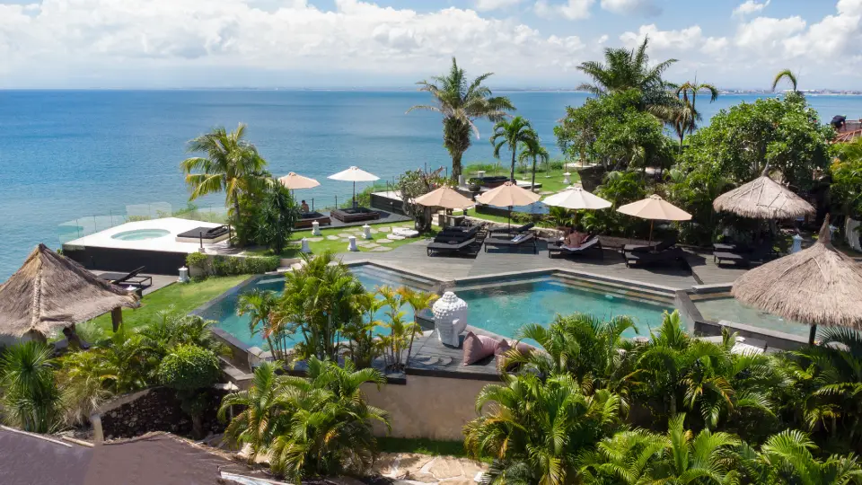Resort pool in Bali with ocean view, palm trees and tropical surroundings