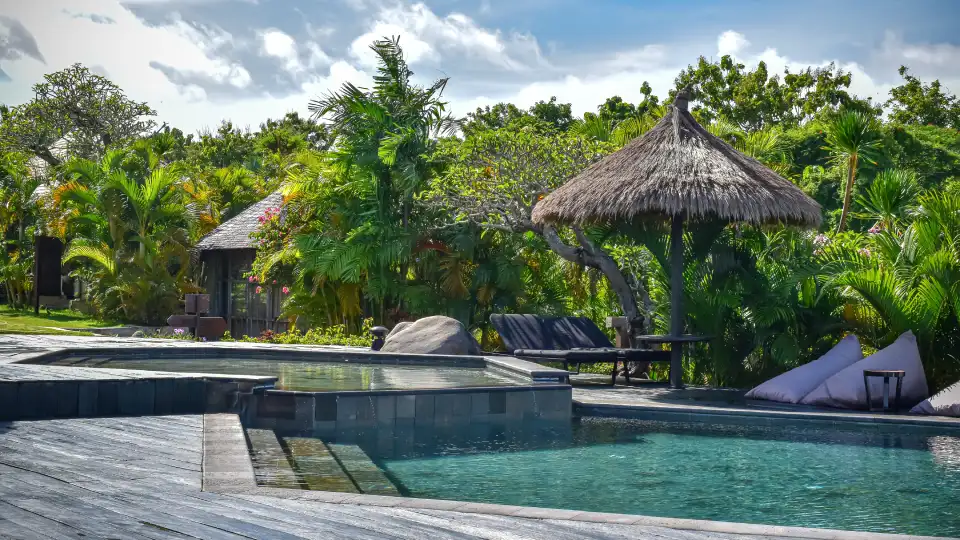 Tropical resort pool in Bali surrounded by greenery and traditional-style roofs