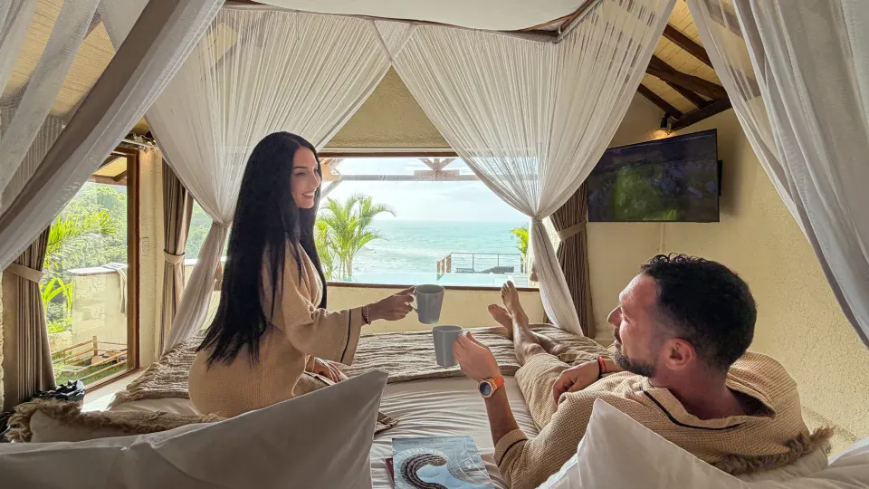 Couple enjoying breakfast in a Bali room with curtains and ocean view