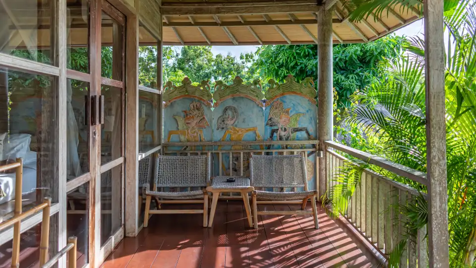 Wooden terrace at a Bali resort with chairs and tropical greenery
