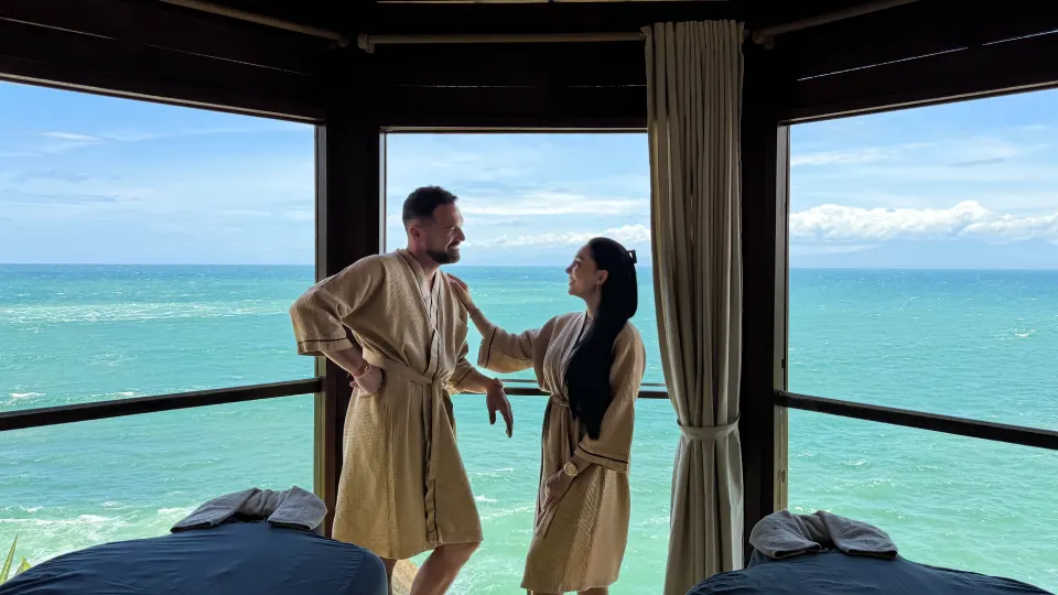 Couple in spa robes enjoying an ocean view inside a Bali spa room