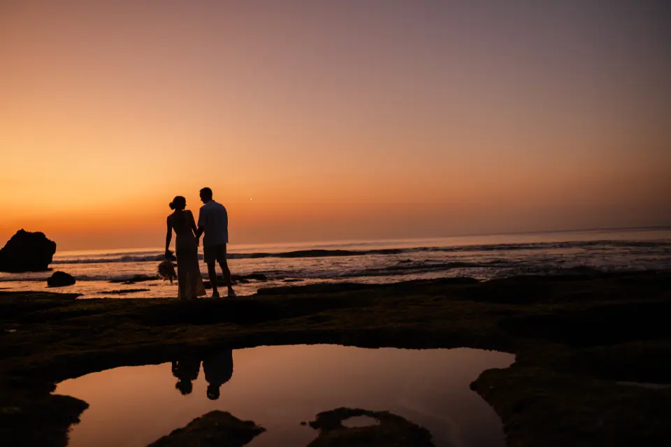 Couple face au coucher du soleil sur la plage à Bali