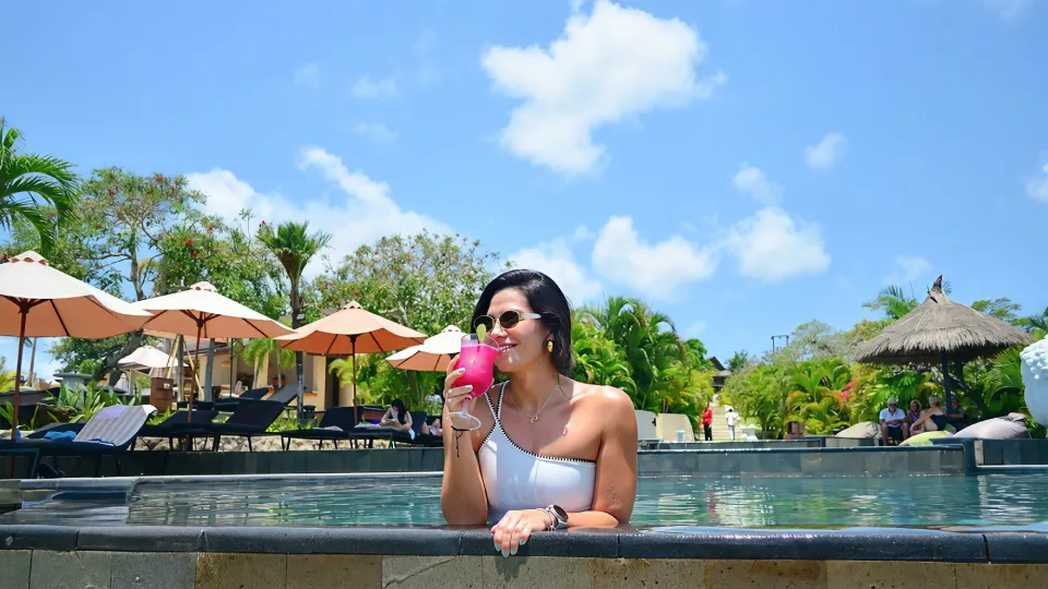 Woman enjoying a cocktail at the pool edge
