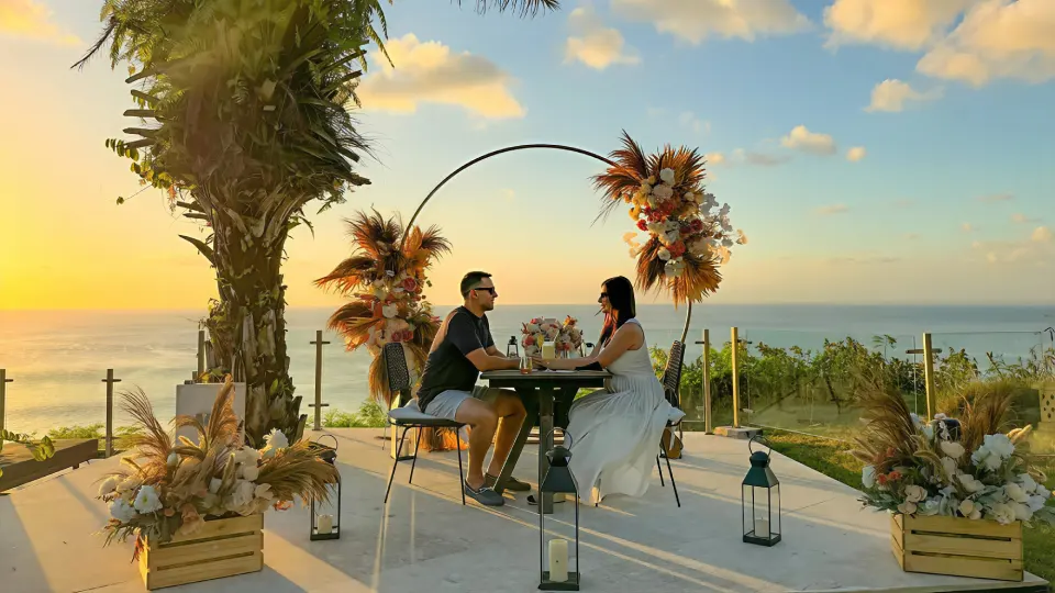 Romantic dinner table set under a floral arch overlooking the ocean