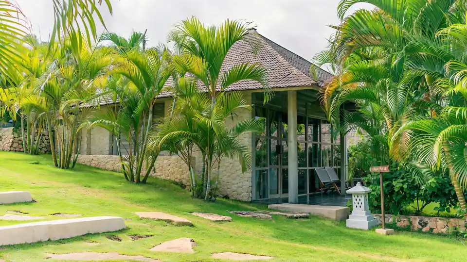 Stone villa exterior surrounded by palm garden